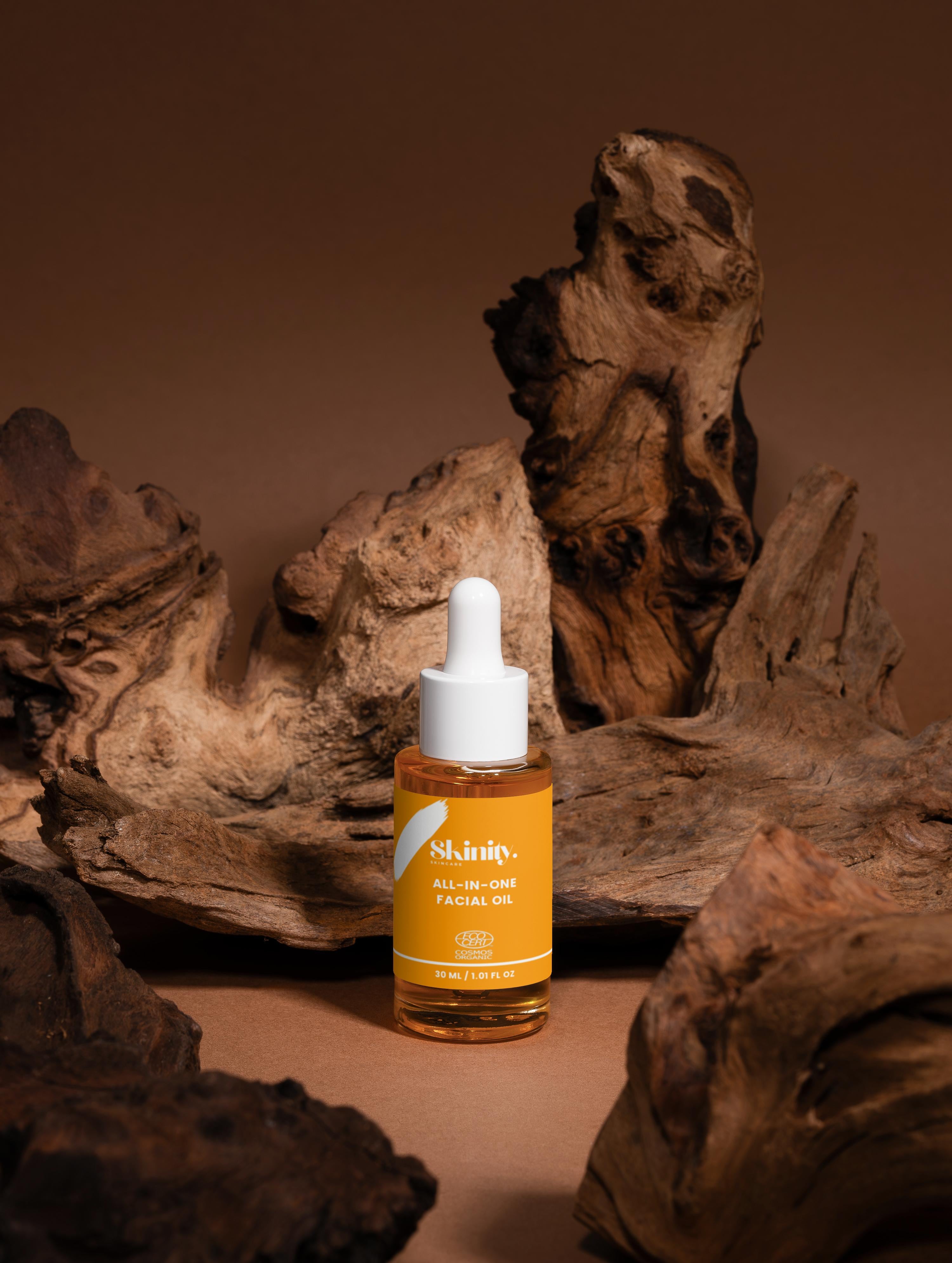 All-In-One Facial Oil for all skin in a dropper bottle surrounded by wooden textures.
