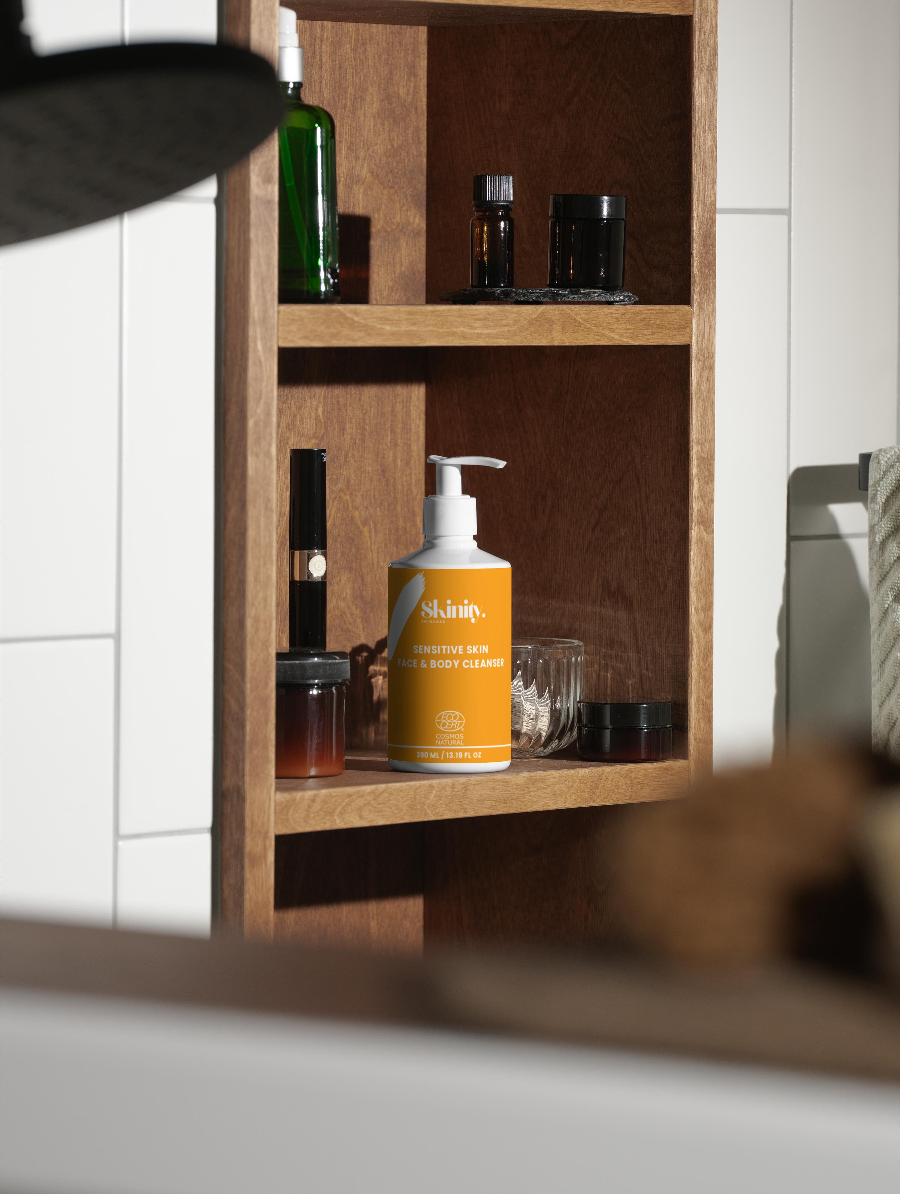 Sensitive Skin Face and Body Cleanser displayed on a wooden shelf alongside various skincare products.