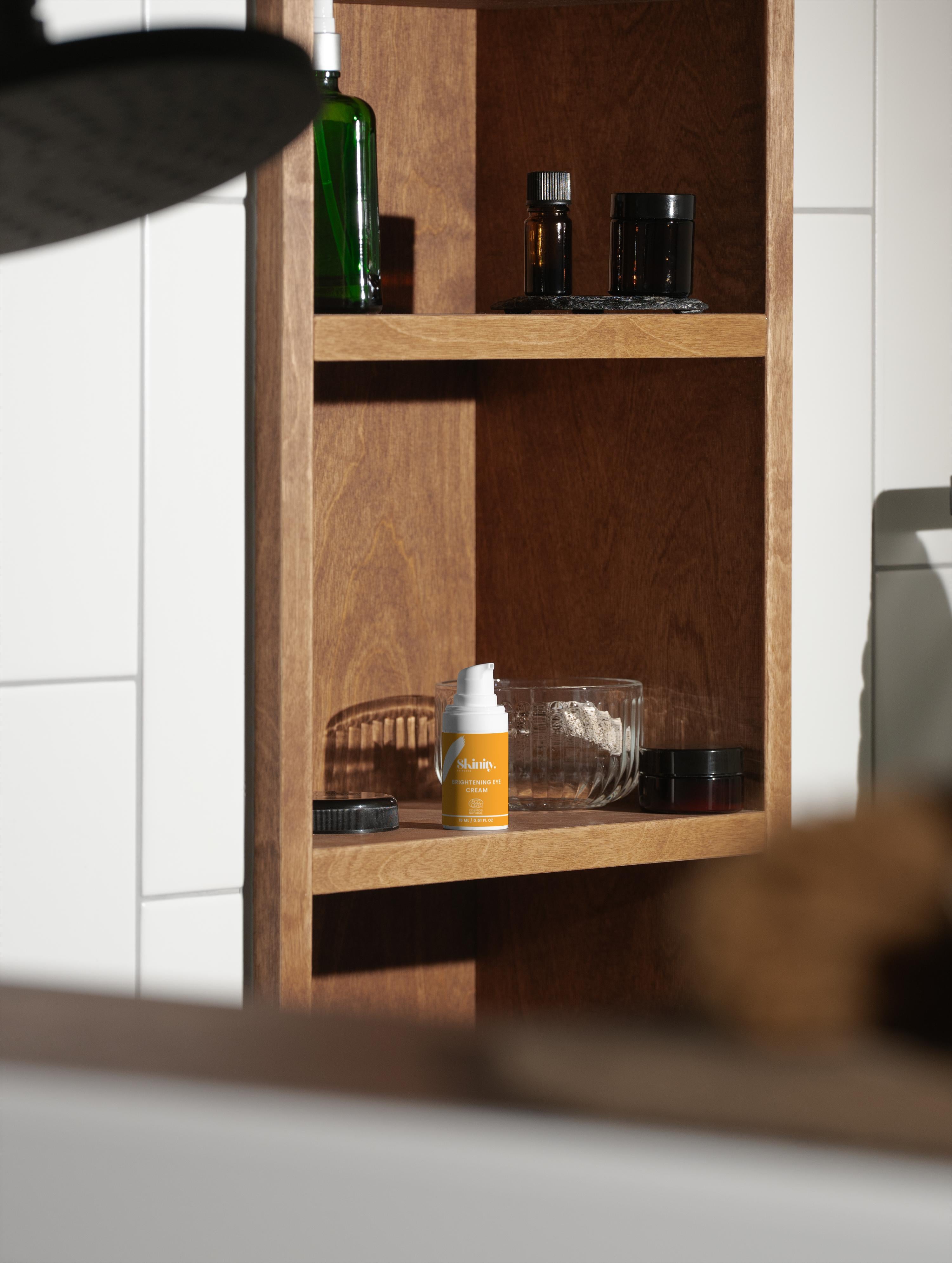 Brightening Eye Cream for All Skincare displayed on a wooden shelf with various skincare products.
