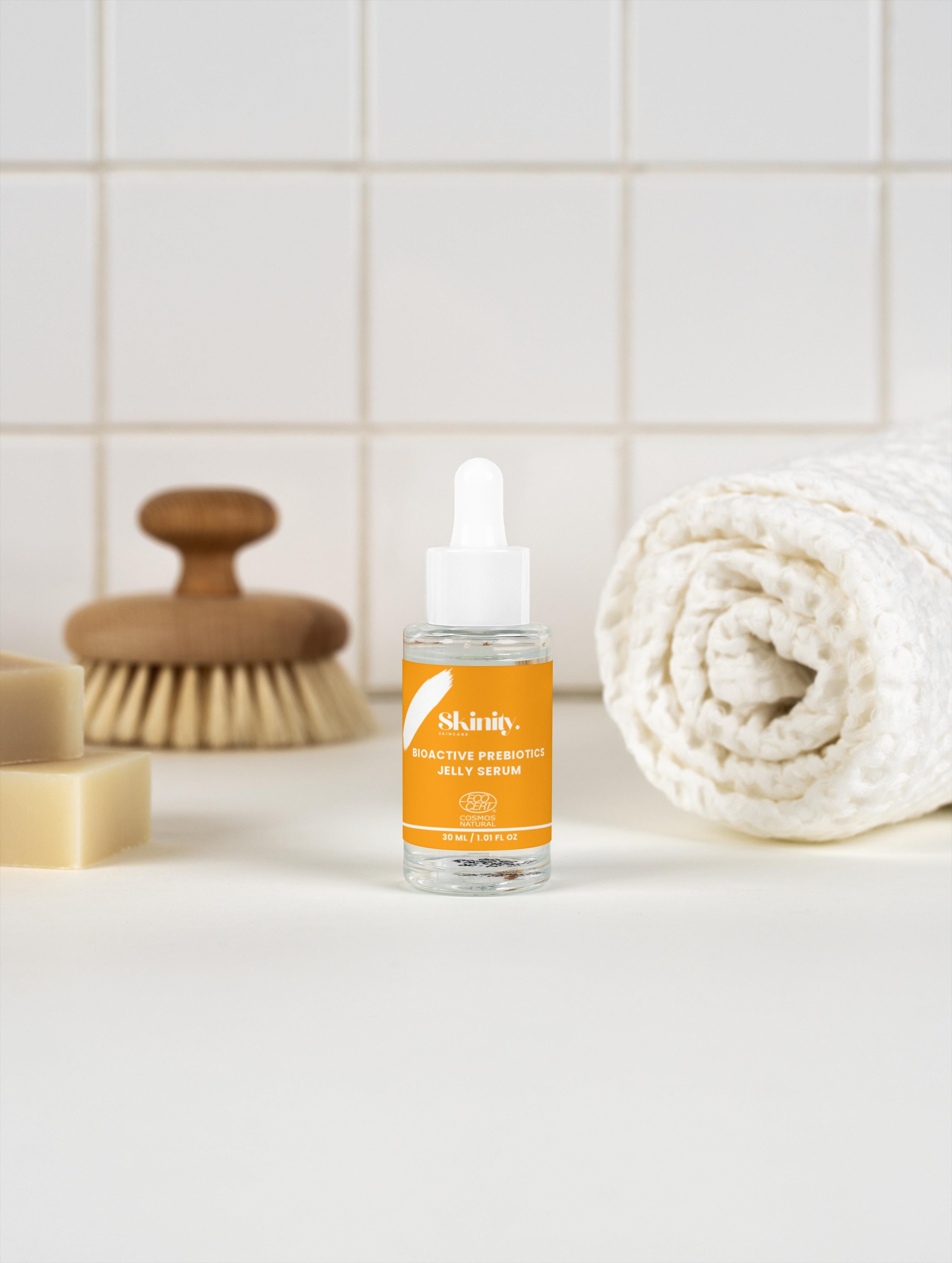 Bioactive Prebiotics Jelly Serum in a glass dropper bottle with a cozy bathroom setting.