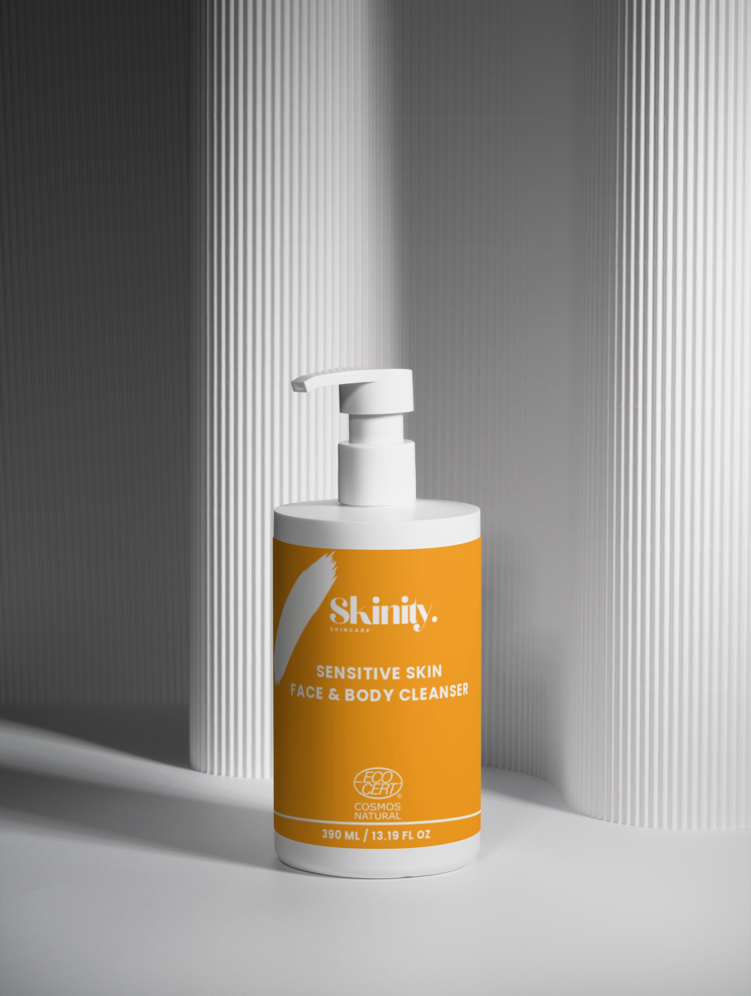 Sensitive Skin Face and Body Cleanser in a pump bottle on a textured surface.