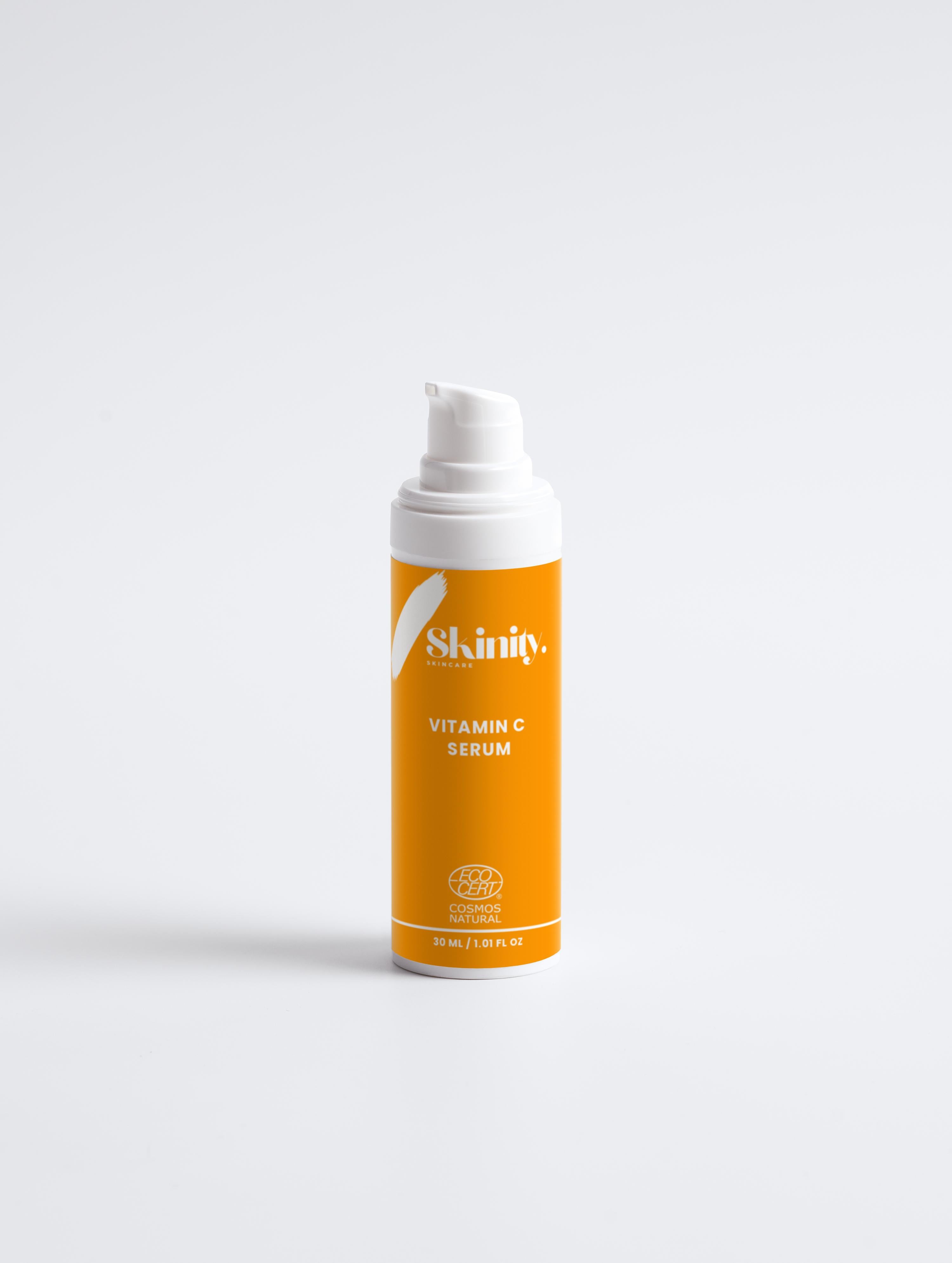 Vitamin C serum for all skin types in an orange pump bottle on a white background.