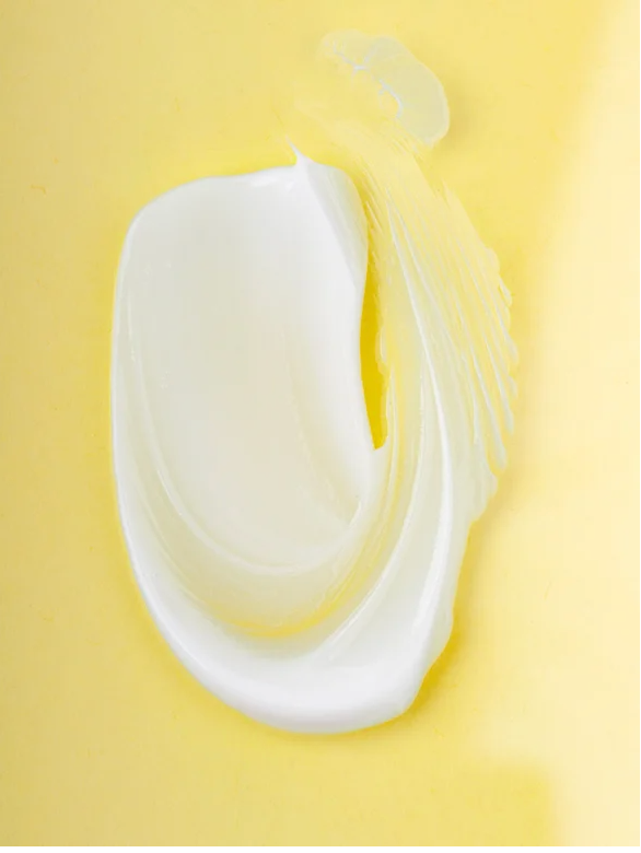 Ceramide Barrier Night Cream for all Skin Types spread on a yellow background, showcasing its creamy texture.