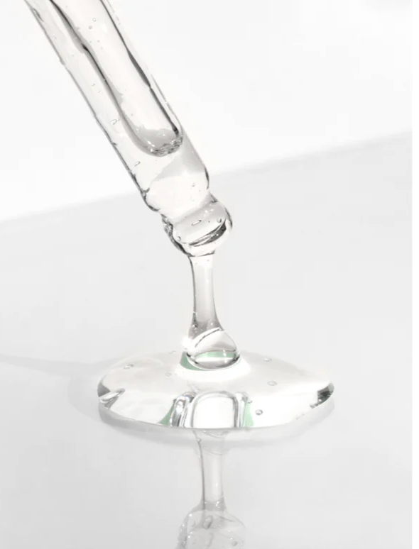 AHA Peeling Concentrate For Skin drip from a dropper on a smooth surface, showcasing its clear, gel-like texture.