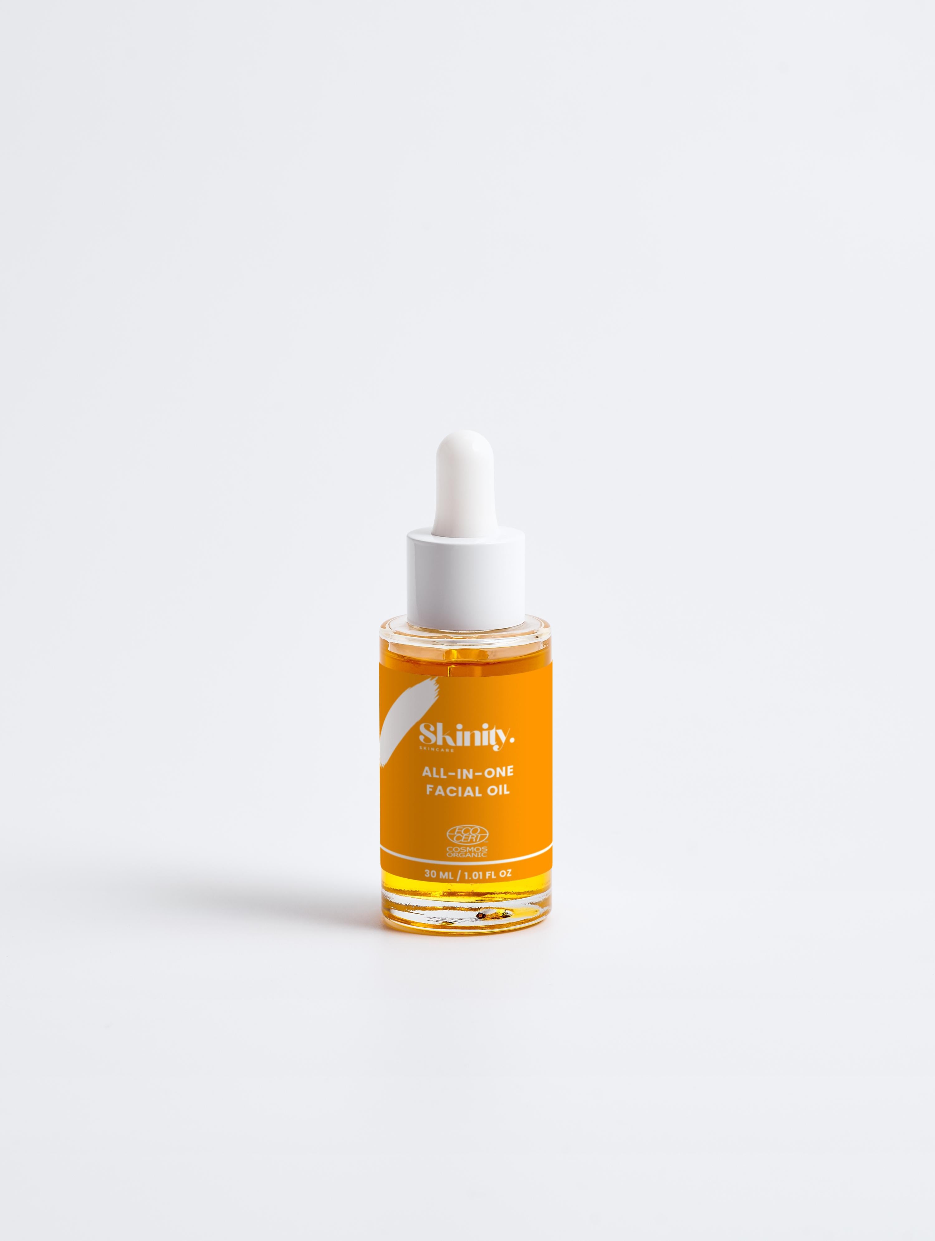 All-In-One Facial Oil for all skin in a glass dropper bottle, showcasing its vibrant orange color.