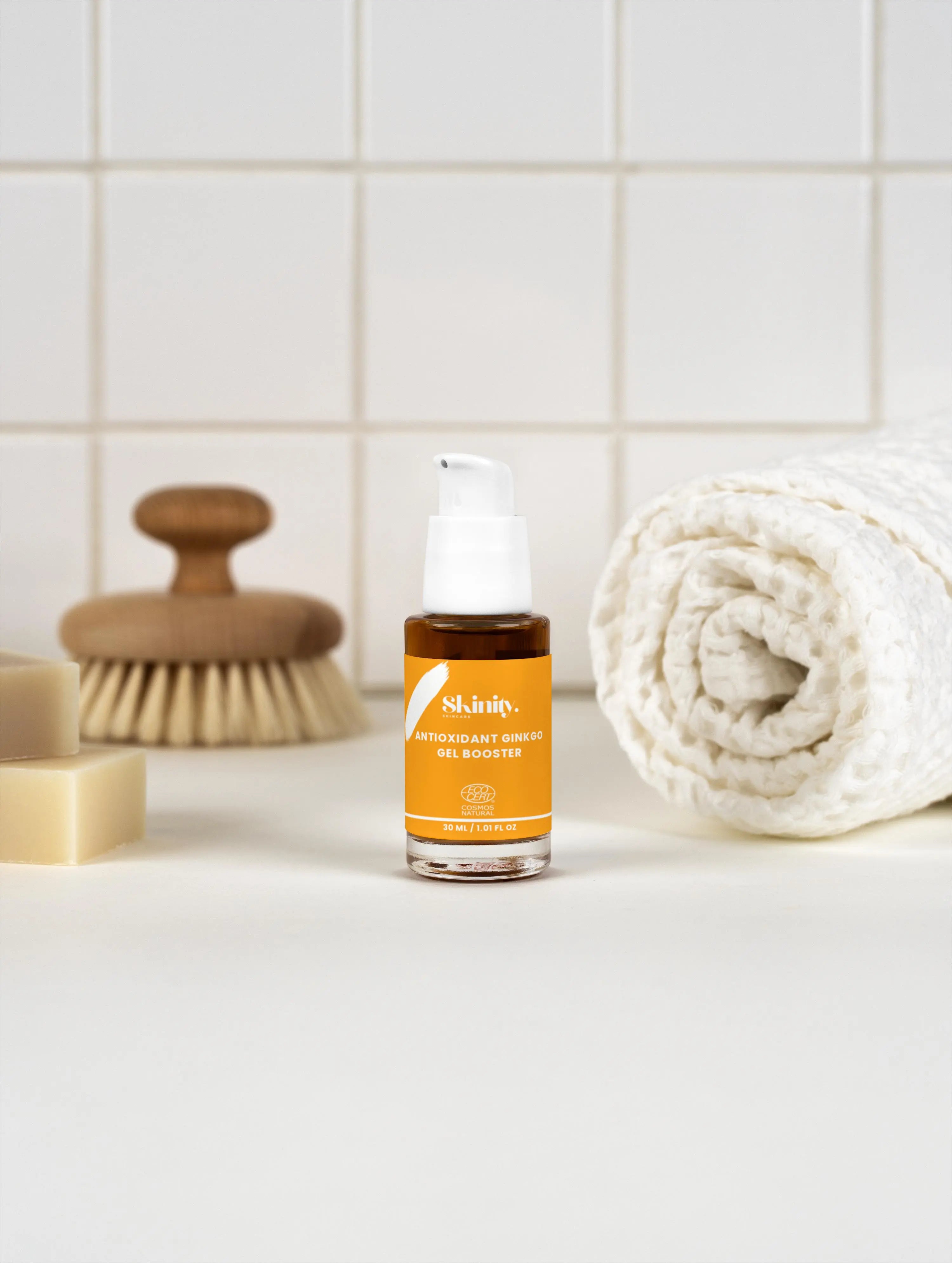 Antioxidant Ginkgo Gel Booster in a stylish bottle on a clean vanity with a towel and cleansing brush.