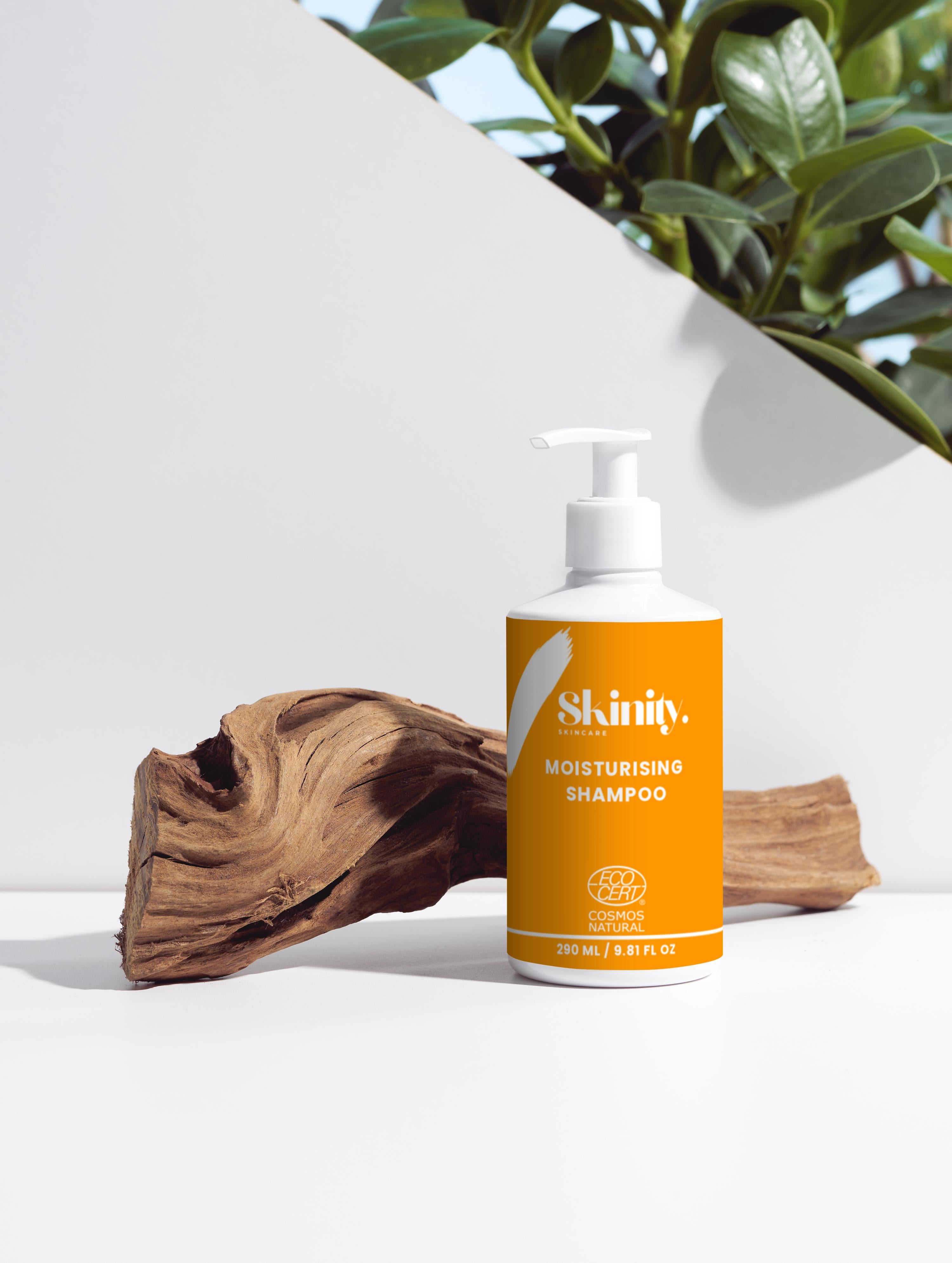 Moisturising Shampoo For All Hair Types bottle displayed on a natural wood piece with green foliage in the background.